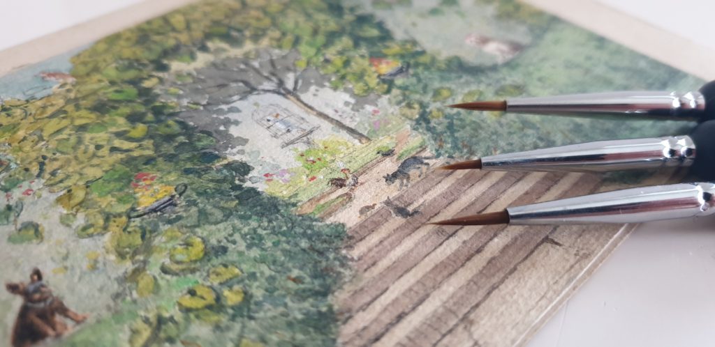 three fine detail brushes on a landscape watercolour painting