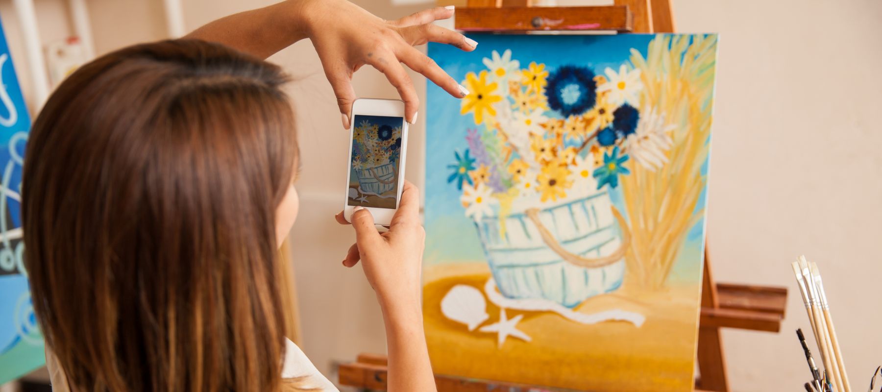 artist taking a picture of her art on a canvas