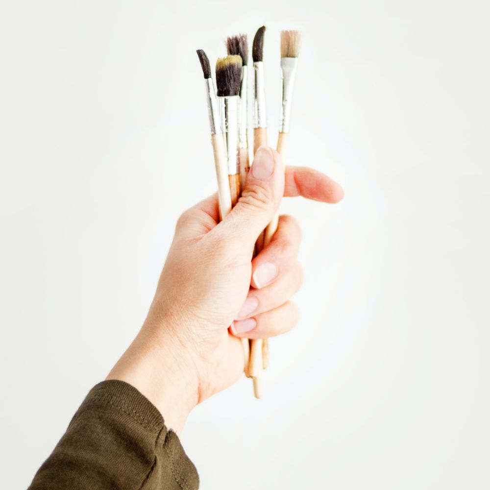 a womans hand holding paintbrushes for use in painting animal fur
